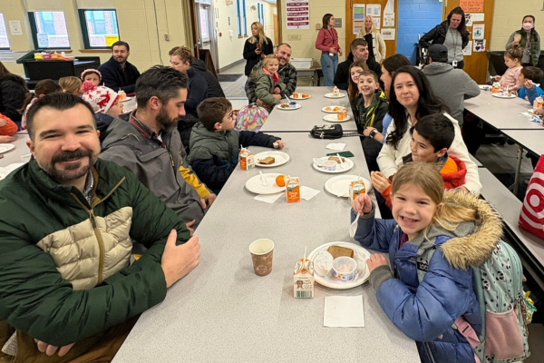 Village Elementary School's 2nd Grade Family Breakfast with students and family members sitting at lunchroom table.