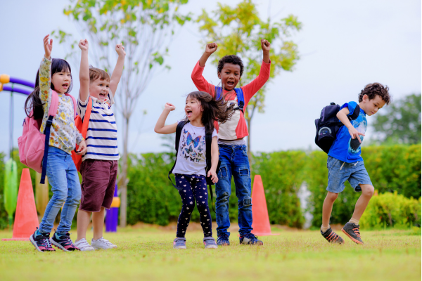 Kids with backpacks jumping in air